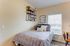Cozy bedroom with modern decor, featuring a stylish wall shelf, comfortable bed with patterned bedding, and a bright window view.