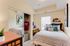 Charming bedroom with mirrored closet, cozy bed, and natural light perfect for relaxation.