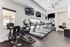 Modern fitness center with multiple treadmills, exercise bikes, and wall-mounted TVs, flooded with natural light.