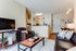 Chic open-plan living area featuring modern leather seating, stylish coffee table, and inviting kitchen with wood cabinetry.