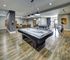 Spacious recreation room featuring a billiards table, ping pong table, and cozy seating area under modern lighting.