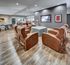 Luxurious community lounge featuring plush leather seating, sleek wood flooring, and vibrant artwork, ideal for relaxation and entertainment.