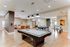 Modern recreation room featuring a sleek pool table, ping pong setup, and cozy leather seating area.