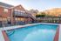 Inviting outdoor swimming pool with brick apartment backdrop, surrounded by comfortable lounge chairs and picturesque hillside views.