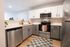 Modern kitchen with sleek gray and white cabinets, stainless steel appliances, and elegant countertops.