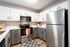 Modern kitchen with sleek stainless steel appliances, elegant two-tone cabinetry, and bright overhead lighting.