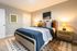Cozy bedroom featuring a comfortable bed with patterned pillows, warm lighting from bedside lamps, and stylish wall art.