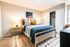 Cozy bedroom featuring a modern wooden bed, accented with stylish pillows and warm lighting, complemented by a spacious closet.
