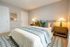 Inviting bedroom with a plush bed adorned with colorful pillows, warm lighting from stylish lamps, and elegant decor accents.