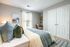 Inviting bedroom with cozy bedding, stylish artwork, and natural light creating a serene atmosphere.