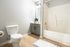 Bright and modern bathroom featuring a sleek vanity, inviting bathtub, and cozy wooden flooring.