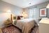Cozy and inviting bedroom with plush pillows, modern wall sconces, and natural light pouring in through the window, creating a serene ambiance.