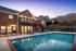 Inviting poolside view of a charming brick apartment complex, featuring a serene evening ambiance and comfortable lounging area.
