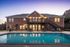 Elegant apartment building with inviting pool and ample outdoor seating, perfect for relaxing evenings.