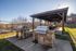 Inviting outdoor BBQ area with stylish stone grills and a covered seating space, perfect for entertaining and relaxing.