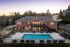 Charming brick apartment building with inviting outdoor pool and ample seating surrounded by lush greenery.