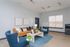 Chic living room with modern decor featuring a stylish leather sofa, plush blue armchairs, and a vibrant area rug, bathed in natural light for a cozy ambiance.