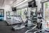 Modern fitness center with state-of-the-art treadmills, elliptical machines, and yoga balls, surrounded by large windows offering scenic outdoor views.