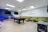 Modern game room with sleek pool table, vibrant seating area, bar stools, and retro arcade machine.