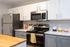 Modern kitchen with sleek stainless steel appliances, white and gray cabinetry, and a wooden countertop island.