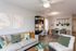 Modern living area with stylish gray sofa, vibrant cushions, chic wall art, and dining space adorned with hanging plants.