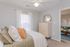 Elegant bedroom featuring plush bedding, stylish dresser with mirror, and a cozy atmosphere bathed in natural light.