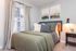 Cozy bedroom with stylish decor, featuring a comfortable bed adorned with plush pillows, soft lighting, and elegant curtains framing a bright window.