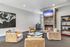Cozy living room with plush chairs, a brick fireplace, vibrant artwork, and ambient lighting, perfect for relaxation.