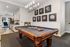 Chic recreational room featuring a stylish billiards table, elegant wall art, and an open kitchenette area with modern decor.