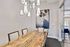 Elegant dining area with a modern chandelier, stylish wood table, and artistic wall painting creating an upscale ambiance.