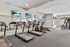 Modern fitness center with state-of-the-art treadmills, elliptical machines, and vibrant wall-mounted TVs.