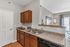 Charming kitchen with elegant countertop and stylish cabinetry, opening to a bright living room with modern decor and large windows.