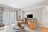 Inviting living room with contemporary decor, featuring a sleek wall-mounted TV, plush seating, and large windows with elegant drapes.