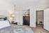 Elegant bedroom with stylish decor, featuring a cozy bed, decorative lamp, sleek dresser, and spacious walk-in closet.