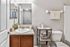 Elegant bathroom featuring a sleek countertop with a modern sink, stylish mirror, and contemporary decor including plants and lotion.