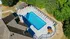 Aerial view of a stunning pool area with pristine blue water, surrounded by lounge chairs and lush greenery, perfect for relaxation and outdoor fun.