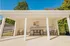 Bright and inviting poolside cabana under a clear blue sky, featuring a cozy seating area with comfortable chairs and a modern table, surrounded by lush greenery.