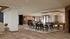 Elegant open-concept entertainment area with modern dining setup, chic bar stools, and a stylish billiards table, featuring warm wooden accents and abundant natural light.