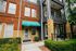 Charming apartment building exterior with red brick and modern design, featuring lush green landscaping and inviting balconies.