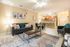 Modern open-concept living room with cozy gray sofa, stylish decor, and adjoining kitchen with warm wood cabinetry.