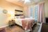 Cozy bedroom with a plush bed, warm ambient lighting, and elegant pink curtains creating a tranquil retreat.