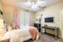 Inviting bedroom with cozy decor, featuring soft pink accents and ample natural light from large windows.