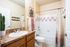Charming bathroom with a modern touch, featuring a granite countertop, elegant fixtures, and a stylishly tiled bathtub.