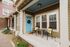 Charming front porch with bright blue door, cozy seating, and inviting decor in a picturesque neighborhood setting.