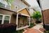Charming townhouse exterior with inviting porch, lush greenery, and modern design elements.