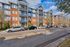 Charming apartment complex with modern design, featuring red brick and blue siding, showcasing spacious balconies and beautifully maintained surroundings.