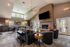 Inviting living space with high ceilings, a modern brick fireplace, chic seating, and natural light from large windows.