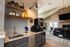 Modern kitchen with sleek granite countertops, elegant open shelving, and cozy living area featuring a stylish fireplace and contemporary lighting.