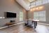 Chic dining room with modern gray walls, large windows, elegant light fixture, and a wooden table complemented by cushioned chairs.