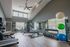 Bright, modern gym with high ceilings, featuring a range of fitness equipment including treadmills, weight benches, and exercise balls surrounded by large windows.